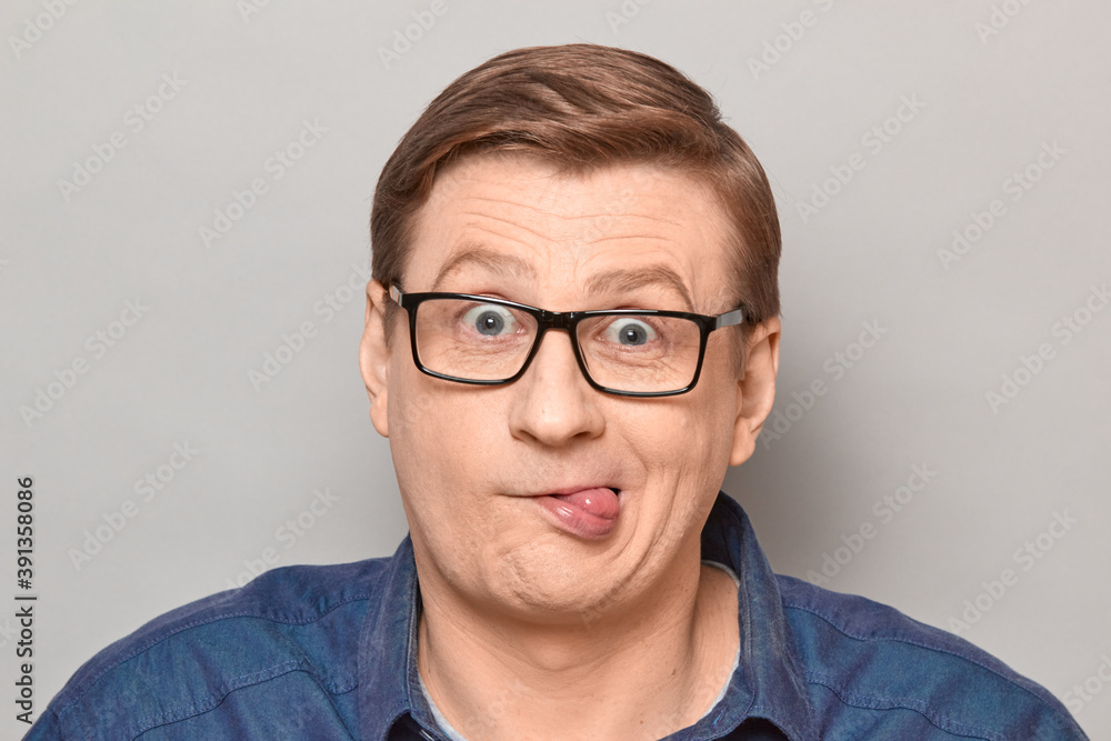 Portrait of funny crazy cheerful man showing tongue and fooling around
