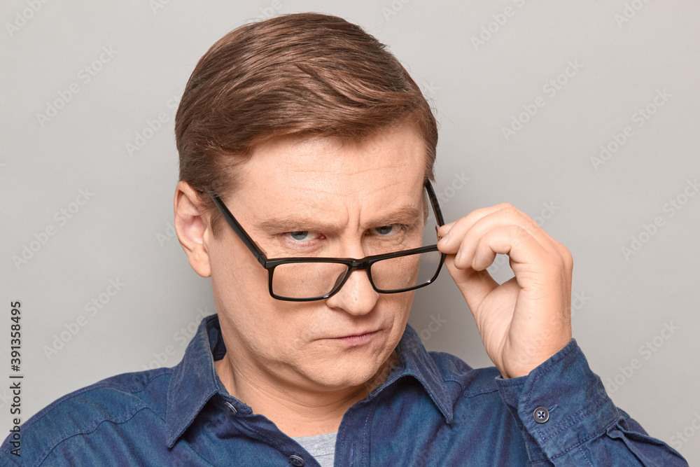Portrait of serious man looking over glasses at something interesting Portrait of serious man looking over glasses at something interesting