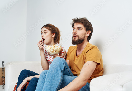 Men women with popcorn in a plate indoors on the sofa