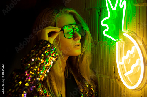Neon Portrait. Retro wave. Blonde girl with glasses looking to light. Neon yellow and green  colors.