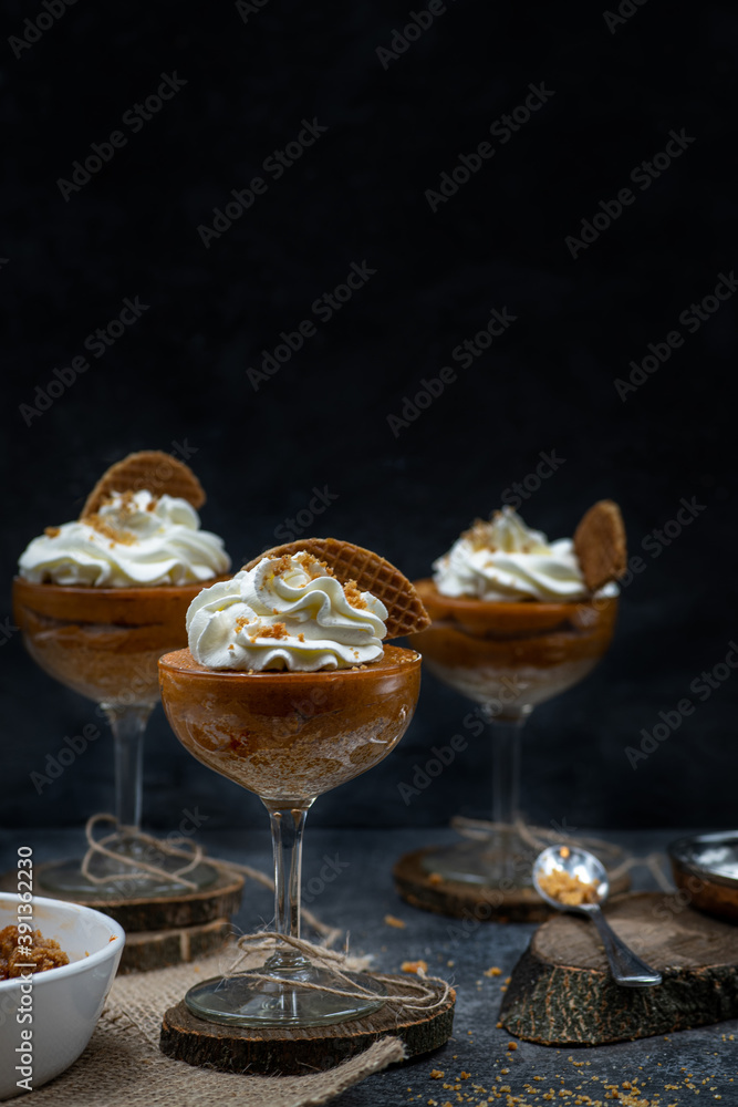 Pumpkin mousse and whipped cream served in tall glasses against black background, copy space