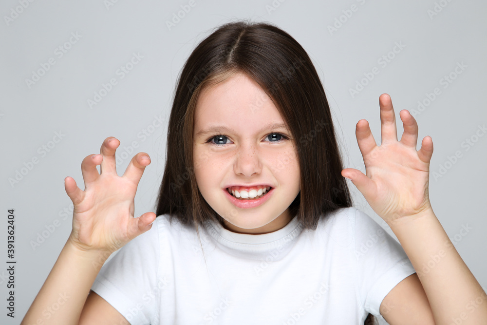 Young girl showing gesture cat claws by hands on grey background Young girl showing gesture cat claws by hands on grey background
