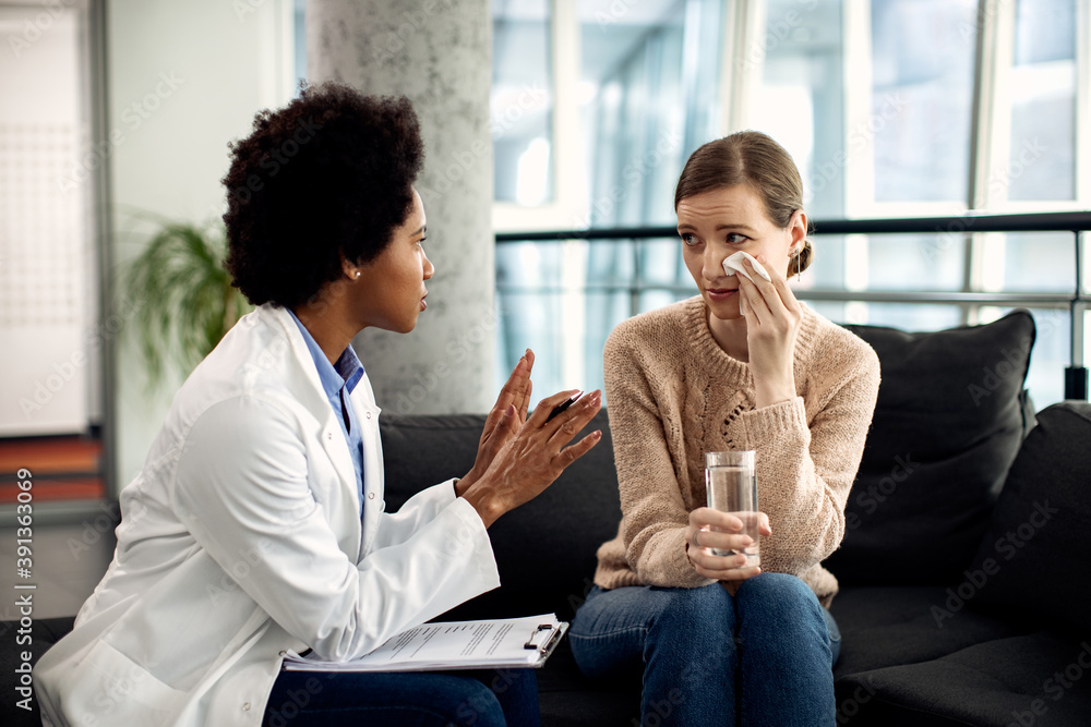 African American counselor talking to a crying woman during psychotherapy session. African American counselor talking to a crying woman during psychotherapy session.