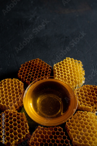 Honey and honeycomb in the form of a flower on black table, top view. space for text