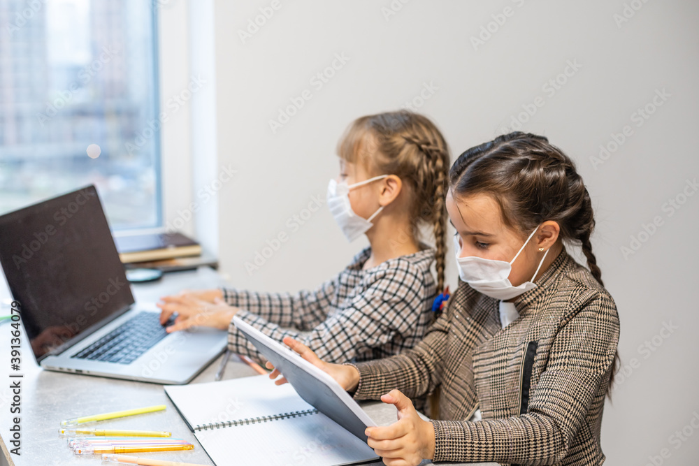 Distance Learning. School Girls At Laptop Wearing Mask Studying Online Sitting at the table at home Distance Learning. School Girls At Laptop Wearing Mask Studying Online Sitting at the table at home