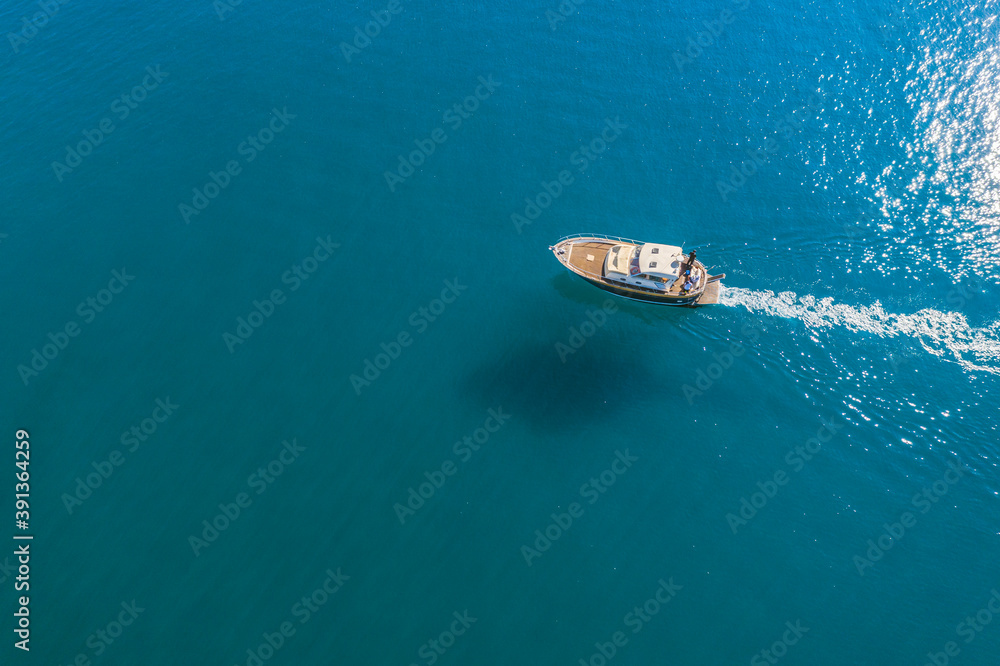 Small fishing boat is sailing on the shallow of mediterranean sea at sunny day- Aerial image with copy space Small fishing boat is sailing on the shallow of mediterranean sea at sunny day- Aerial image with copy space