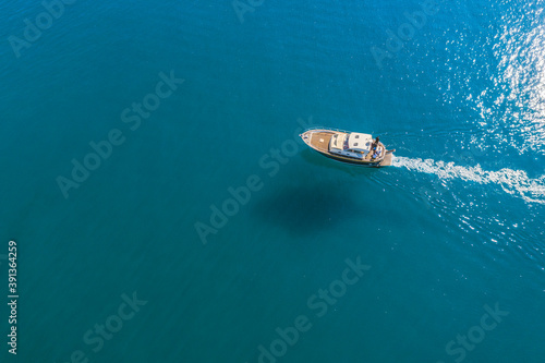 Small fishing boat is sailing on the shallow of mediterranean sea at sunny day- Aerial image with copy space © Alex Kiriuchkov