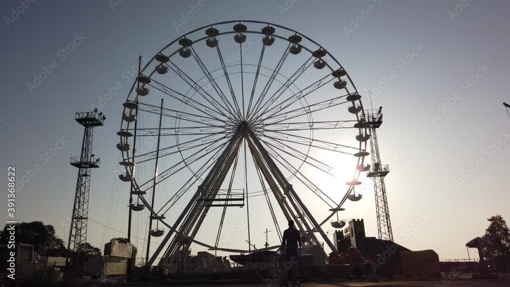 Multiple shots of a young man riding infront of a ferris wheel Multiple shots of a young man riding infront of a ferris wheel