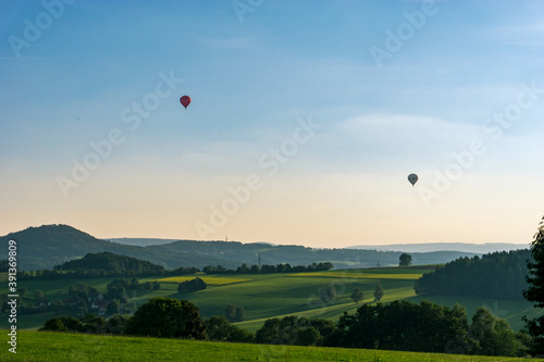 Two small hot air ballons over beautiful hilly landscape