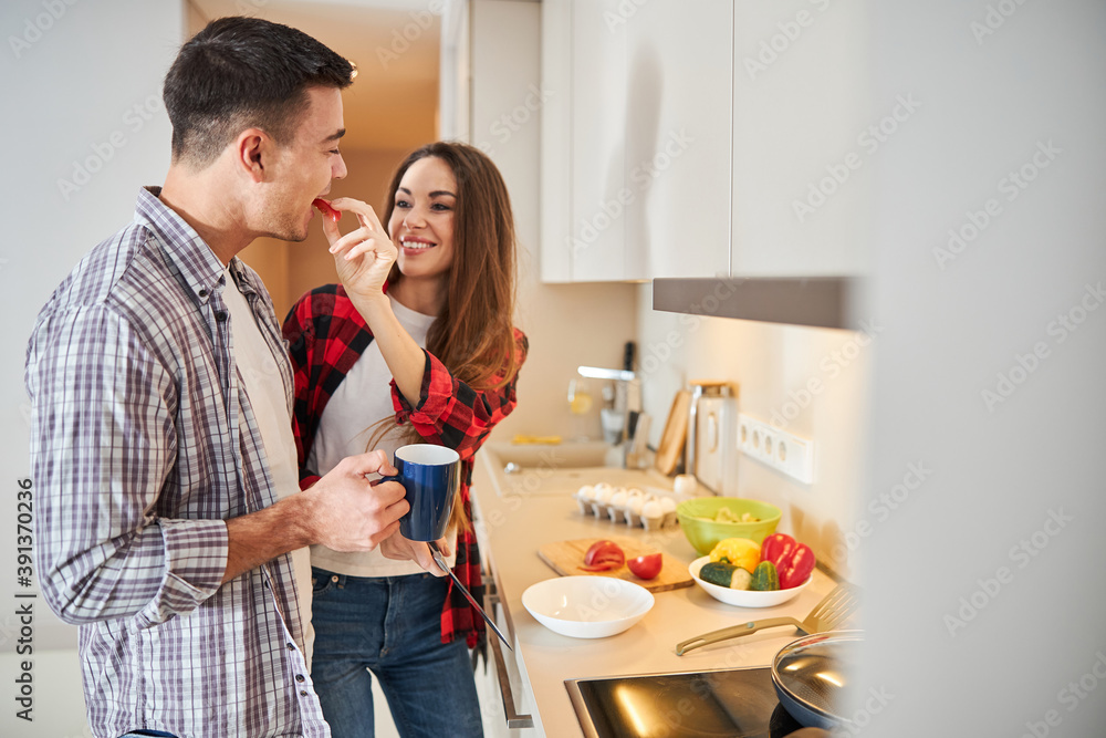 Man eating the sliced vegetable from his wife hand
