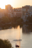 Fountain light by golden hour on a lake against modern buildings