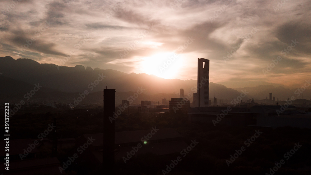 drone shot of a skyscraper against the Monterrey cityscape at the sunset