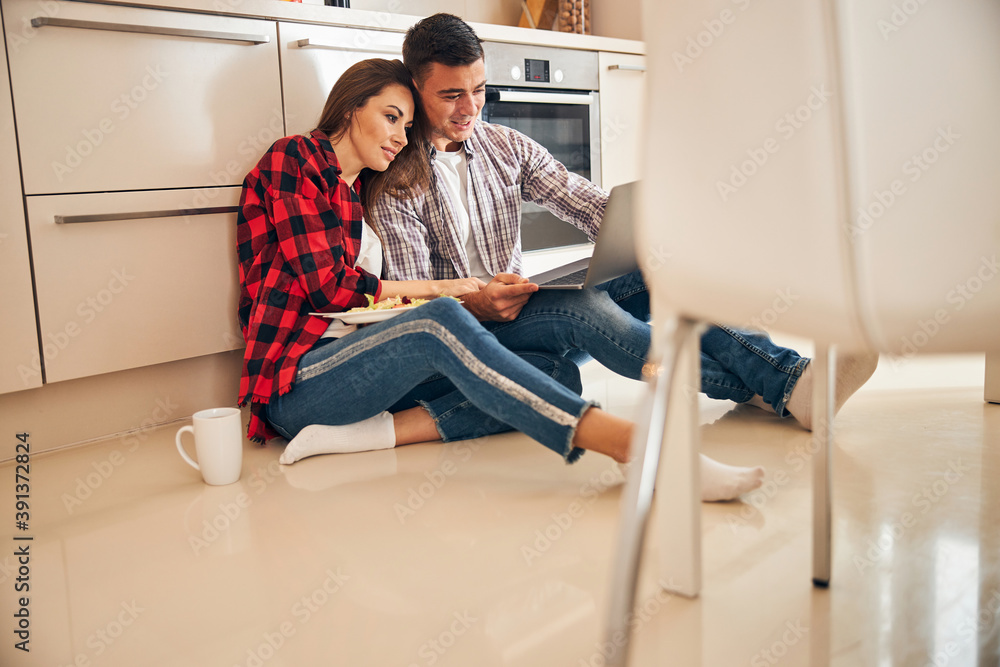 Smiling man and his spouse looking at the laptop screen