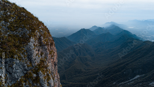 Cerra de la Silla drone view, misty mountain chain in the background and a rocky slope in front