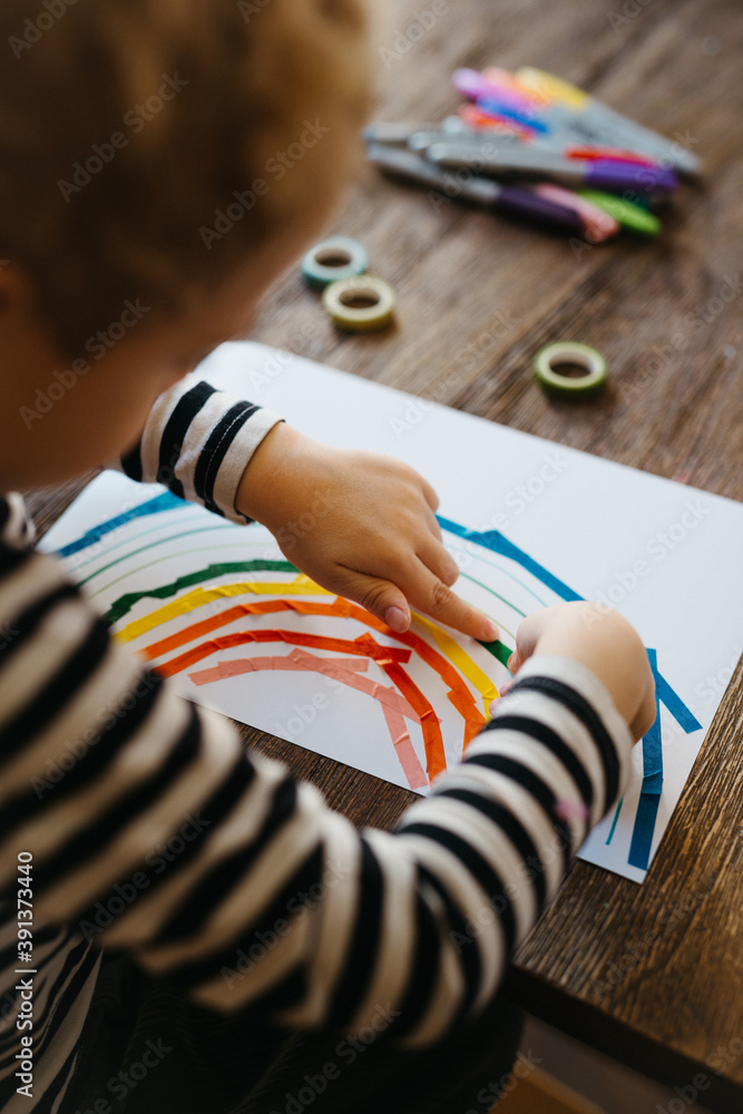 boy crafting a rainbow with colorful washi tape boy crafting a rainbow with colorful washi tape