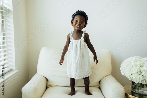 Little girl in white dress playing in chair photo