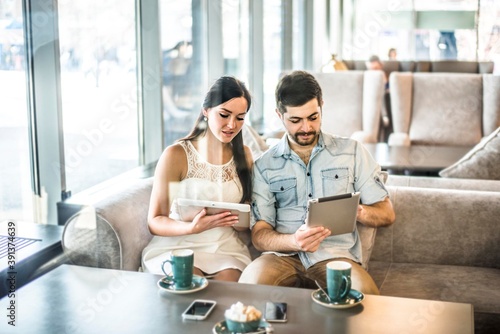 Serious Couple love sit on sofa couch look at tablet computer Woman show screen with image or site Family, technology internet and happiness concept concentrated couple with smartphones photo