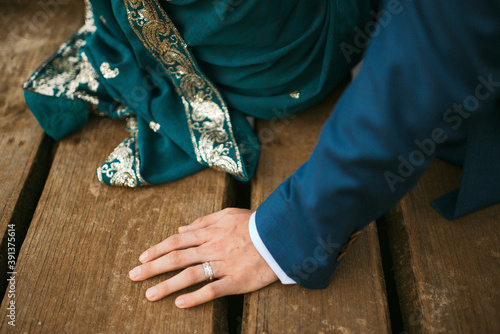 Indian bride and groom sitting next to each other outdoors on wooden jetty photo