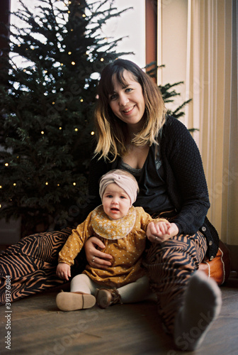 mother and her daughter before the christmas tree with string lights photo