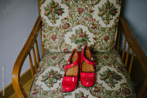 Red heels with bow on a vintage retro looking chair sofa indoors photo