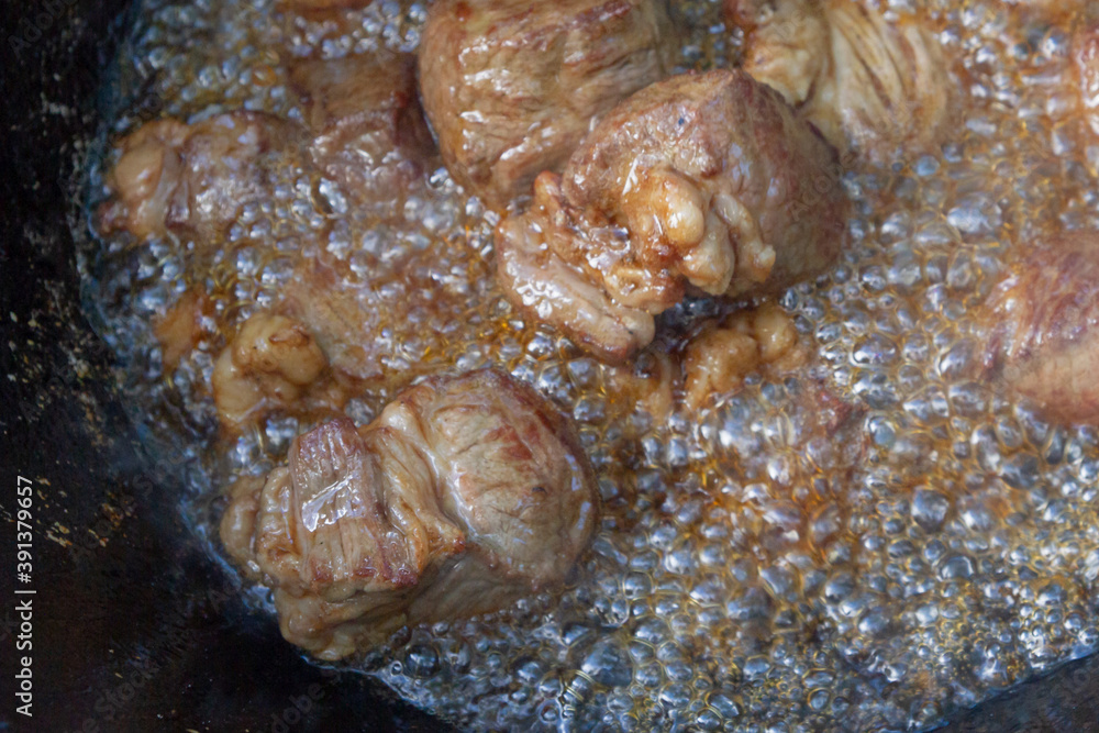 Cooking pilaf in a cauldron on the grill outside in the summer Cooking pilaf in a cauldron on the grill outside in the summer