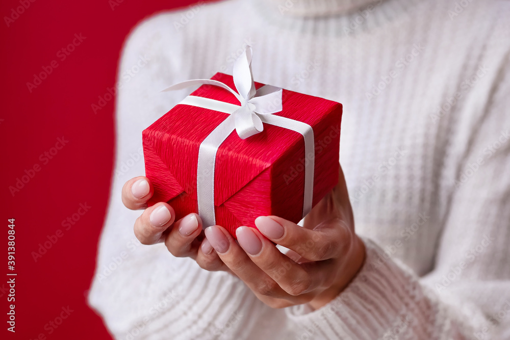 Female hands holding red gift box with white ribbon and bow on the red background. Christmas and New Year holidays. Valentine's Day and Birthday. Surprise, greeting, celebration, present. Isolated Female hands holding red gift box with white ribbon and bow on the red background. Christmas and New Year holidays. Valentine's Day and Birthday. Surprise, greeting, celebration, present. Isolated