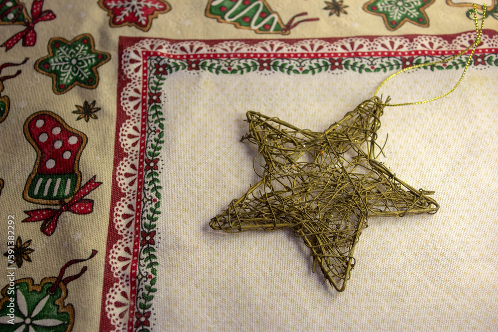 A golden star christmas decoration made of tangled wire on top of a thematic tablecloth