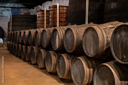 Old porto lodge with rows of oak wooden casks for slow aging of fortified ruby or tawny porto wine in Vila Nova de Gaia, Portugal