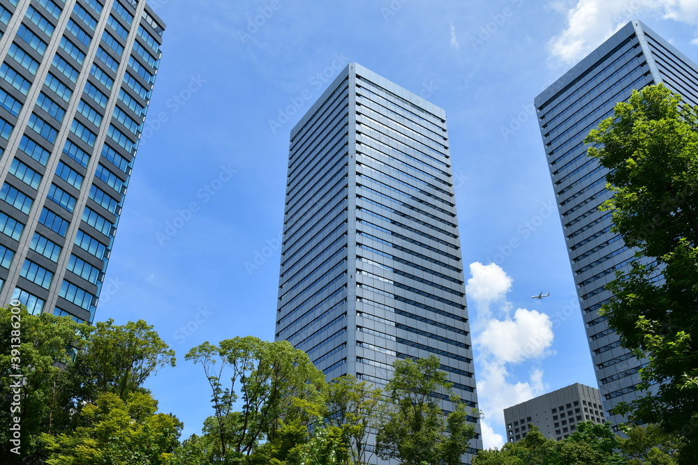大阪ビジネスパークのビル群の上空を飛ぶ飛行機