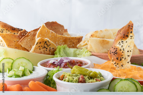 Various dips including buffalo chicken, guacamole and salsa with crisp breads and vegetables for dipping