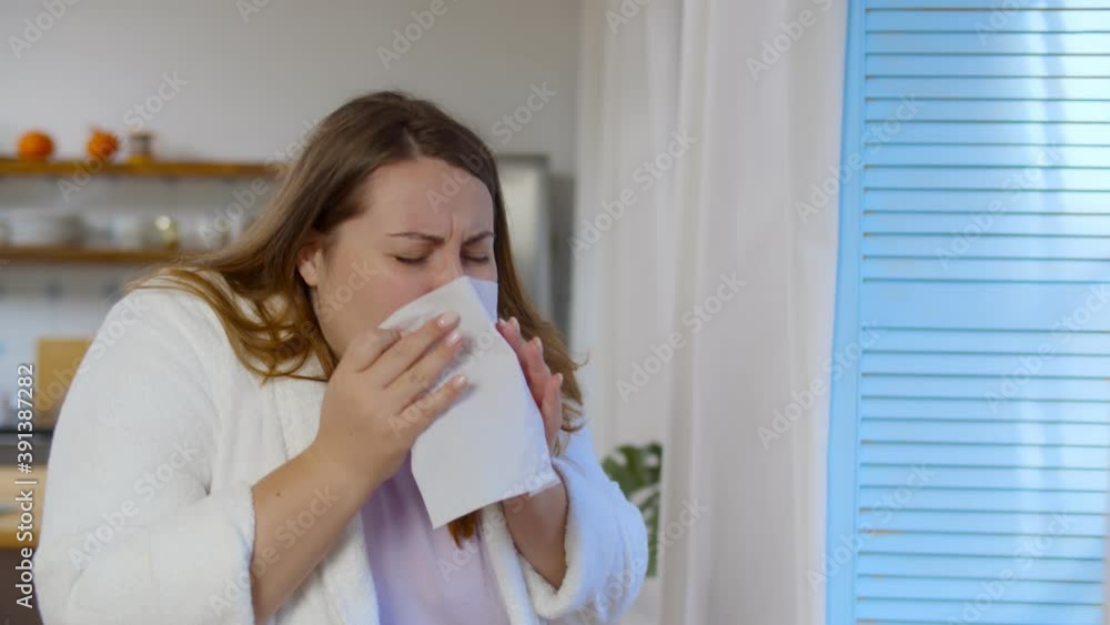 Sick overweight woman using tissue to sneeze and blowing her nose at home having allergy Sick overweight woman using tissue to sneeze and blowing her nose at home having allergy