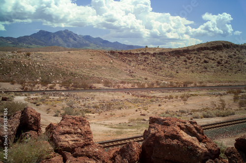 Train tracks cut through a rocky desert canyon cloudy skies
