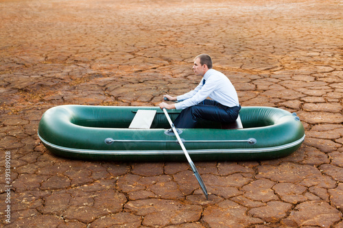 businessman in boat rocks looks bright future symbol crisis stagnation losses braking difficulties environmental disaster water scarcity drought man will rows home for shore in paddle powered row