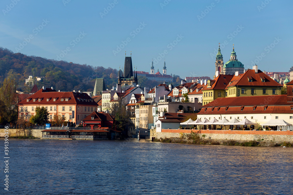 Obraz premium Autumn colorful Prague Lesser Town with St. Nicholas' Cathedral above River Vltava in the sunny Day, Czech Republic