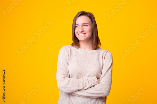 Portrait of smiling young woman with crossed arms looking away.
