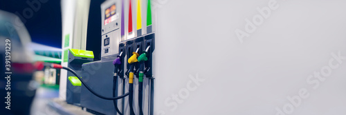 Long Banner for the fuel industry. A gas hose is installed in a car at a night gas station with a store in the background and bright lights.