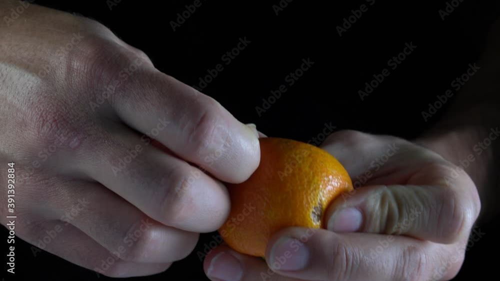 Mandarina mostrada a mano con plano en detalle con fondo negro en 4k de resolución.
