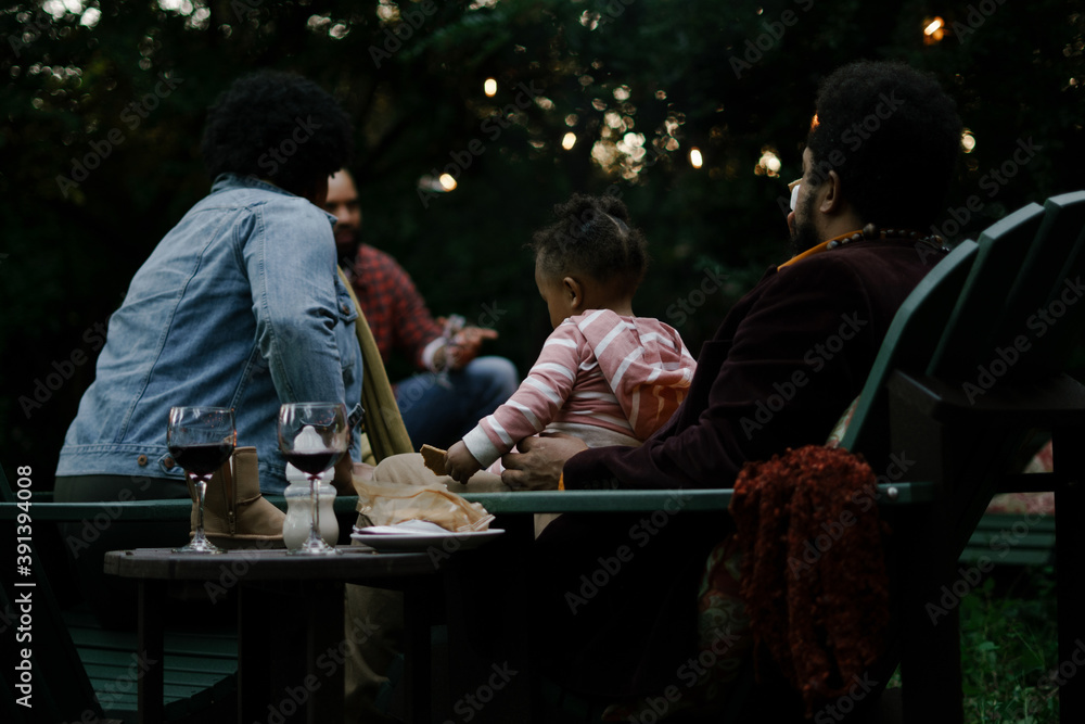 Friends gathered for evening party in backyard around firepit Friends gathered for evening party in backyard around firepit