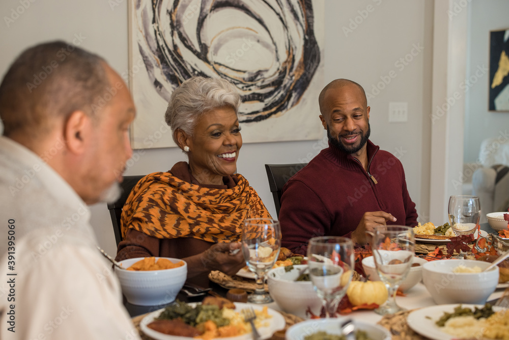 Multigenerational black family eating Thanksgiving dinner together at
