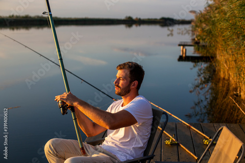 Handsome man fishing on a lake at the sunset.