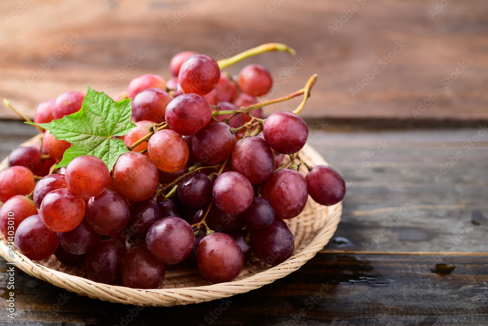 Fresh red grapes fruit in a basket on wooden background Fresh red grapes fruit in a basket on wooden background