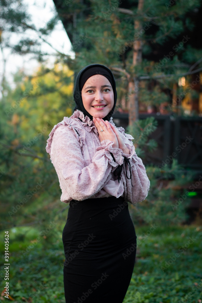 Muslim woman in hijab on the background of trees. Pink blouse and black skirt. Beautiful young woman. Muslim woman in hijab on the background of trees. Pink blouse and black skirt. Beautiful young woman.