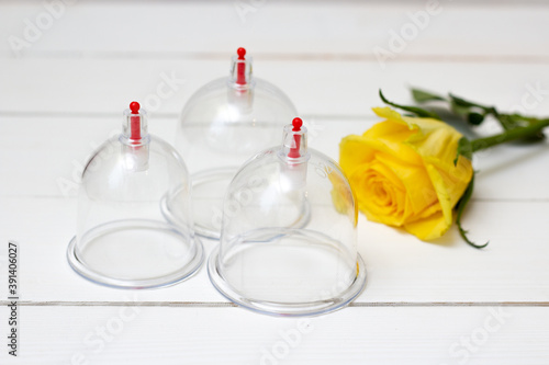 Jars for hijama on a white wooden background and yellow flowers. Bloodletting. Sunnah treatment. Islam. Yellow rose