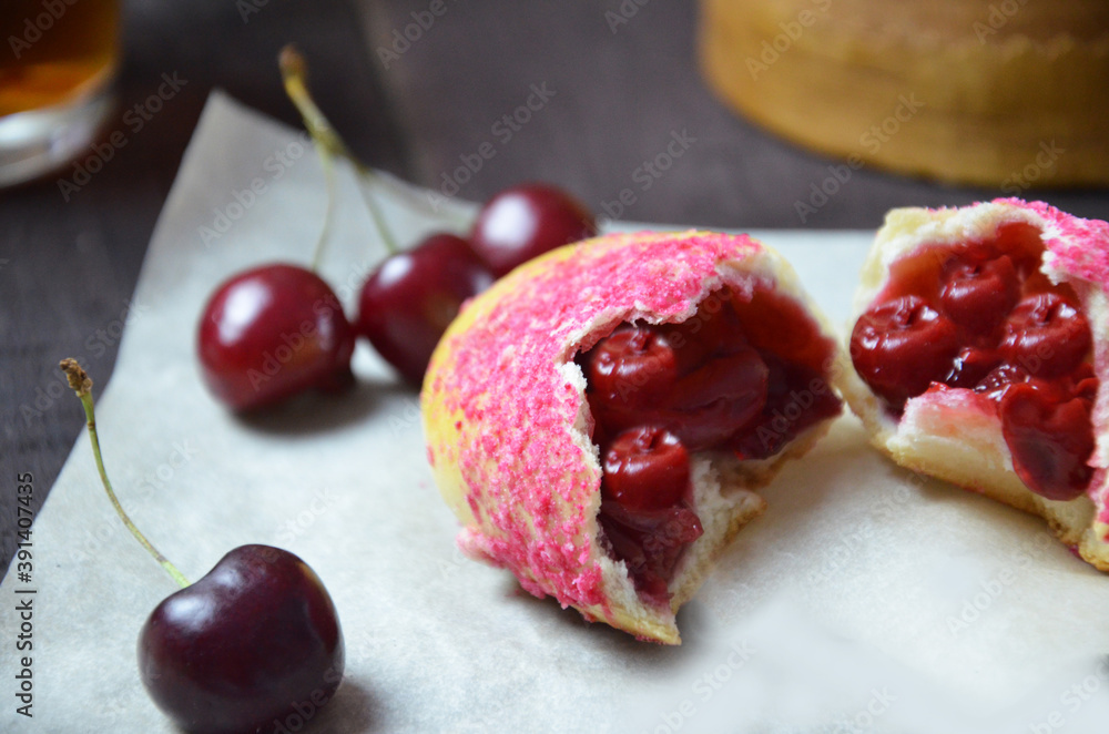 Cherry homemade russian pies on wooden background and cup of tea. with cherry in the basket Cherry homemade russian pies on wooden background and cup of tea. with cherry in the basket