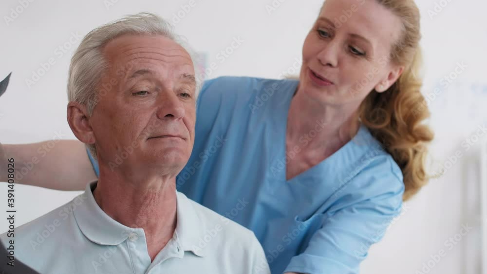 Close up of female doctor putting brace on neck of elderly Caucasian man sitting on exam couch in medical office Close up of female doctor putting brace on neck of elderly Caucasian man sitting on exam couch in medical office
