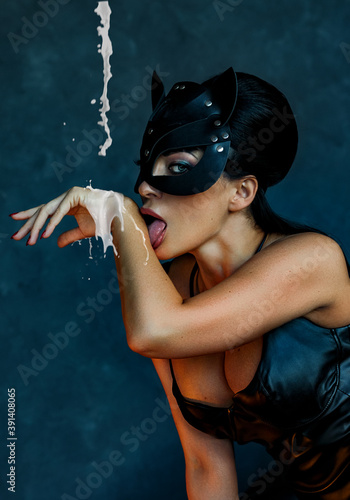 Sexy girl in leather cat mask licks milk