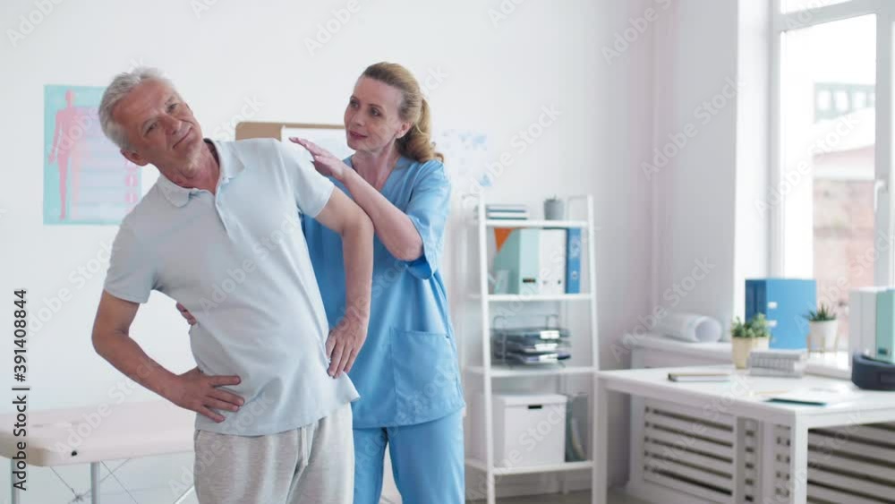 Medium shot of Caucasian old man exercising with the help of female physiotherapist Medium shot of Caucasian old man exercising with the help of female physiotherapist