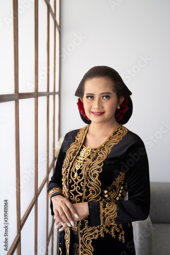 A portrait of a costume traditional Javanese woman. Standing by the window photo