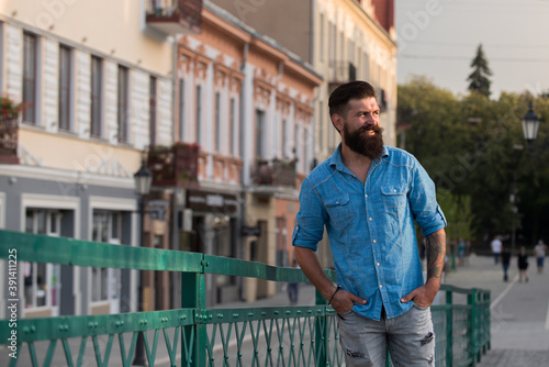 Portrait of fashionable well dressed man with beard posing outdoors looking away  confident and focused mature man in shirt standing outside at street  elegant fashion model.