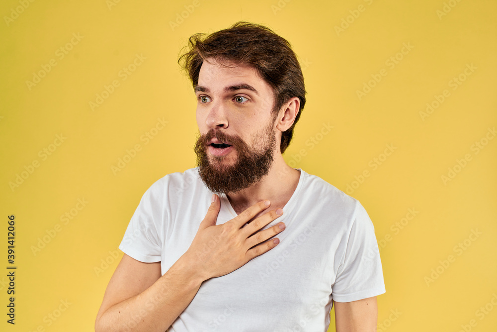 A man in a white t-shirt gestures with his hands lifestyle cropped view yellow background more fun A man in a white t-shirt gestures with his hands lifestyle cropped view yellow background more fun